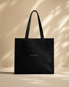 Model carrying XEMORIX XMRX-035 black signature tote bag with centered logo on clean luxury background