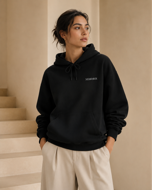 XEMORIX XMRX-010 black minimalist hoodie with left chest logo and branded neck label on a luxury beige background