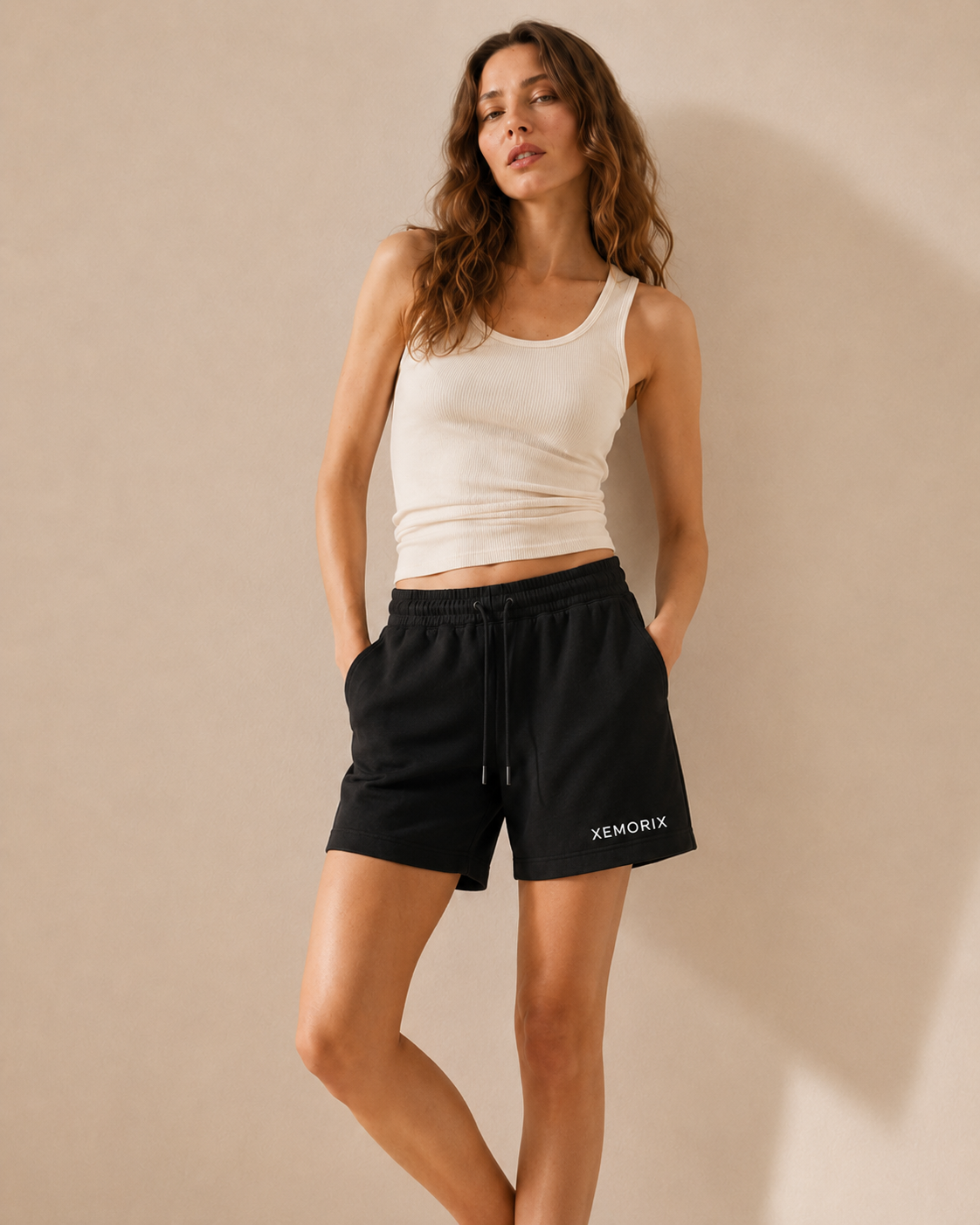 XEMORIX XMRX-072 black minimalist shorts with visible front logo on a beige luxury background